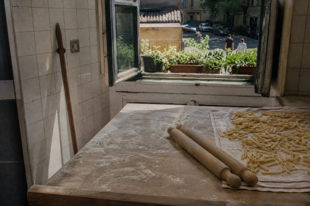 A flour-dusted kitchen counter after a cooking class with rolling pins and cut pasta strips