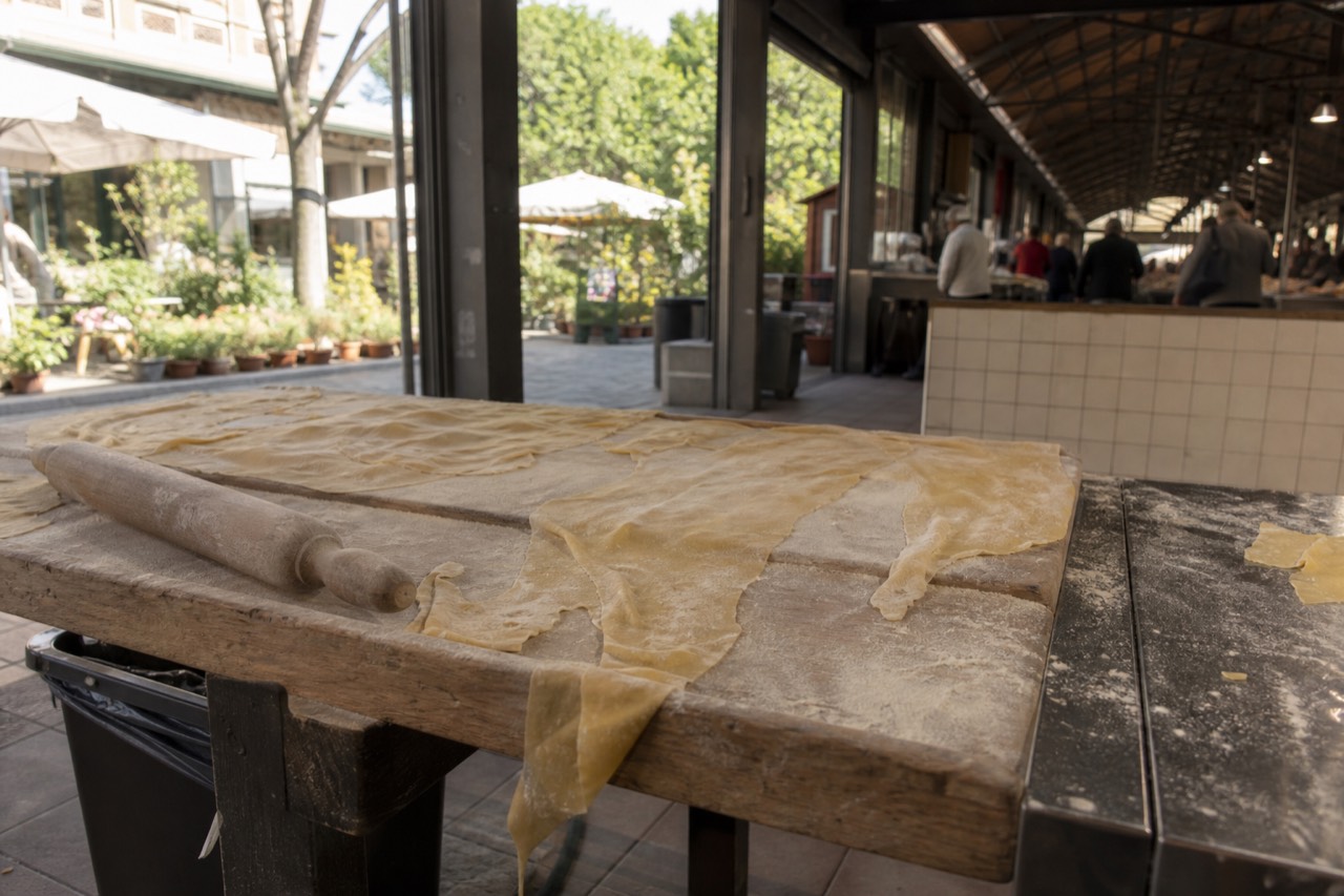 Fresh pasta sheets and a rolling pin on a wooden kitchen counter