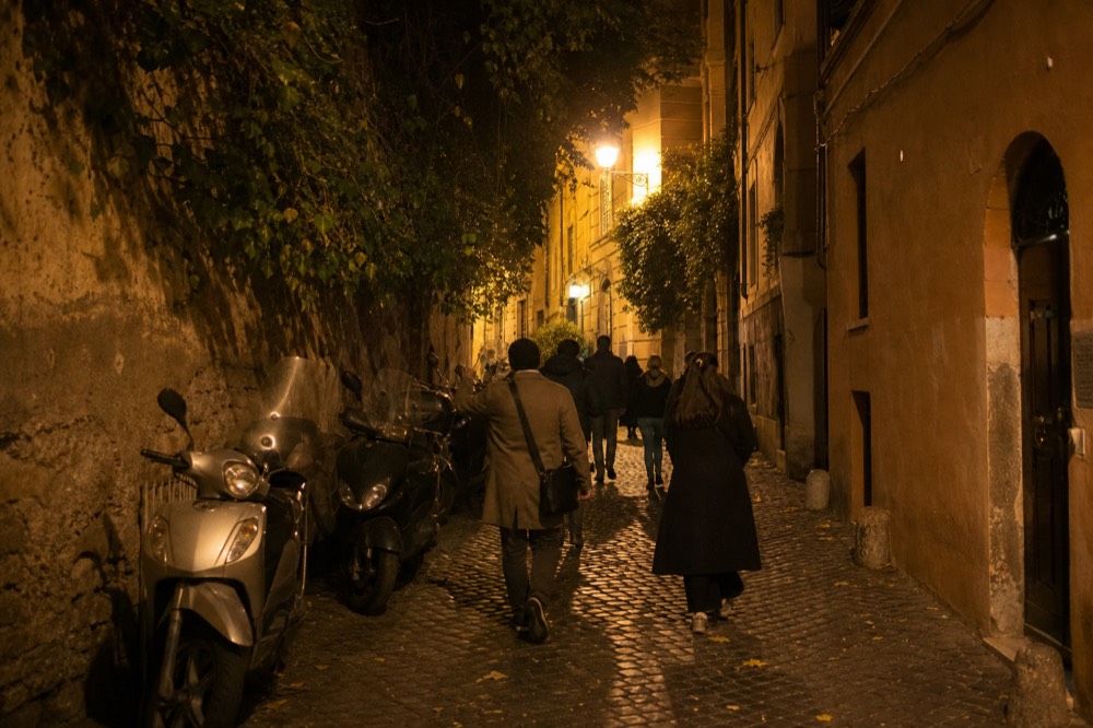 Guide leading a small group down a narrow lamplit Trastevere lane in the evening