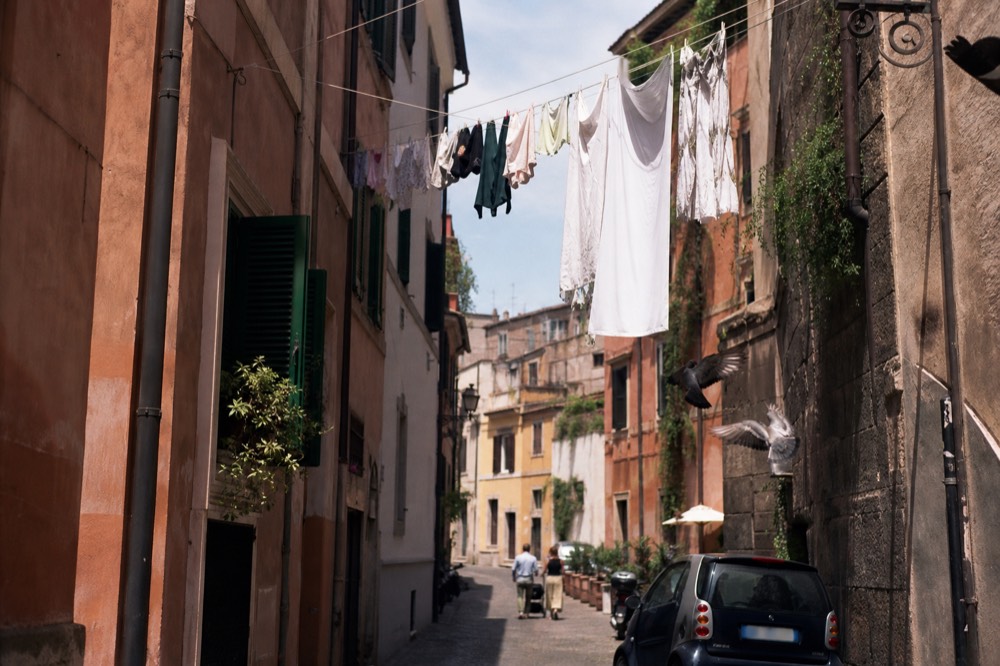 Cobblestone street in Trastevere with laundry hanging between warm colored apartment buildings