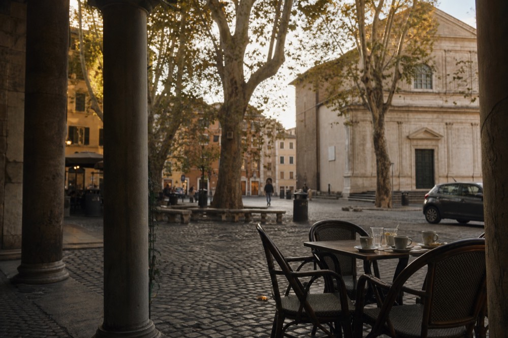 Evening light on a Trastevere square with outdoor tables and a stone church facade
