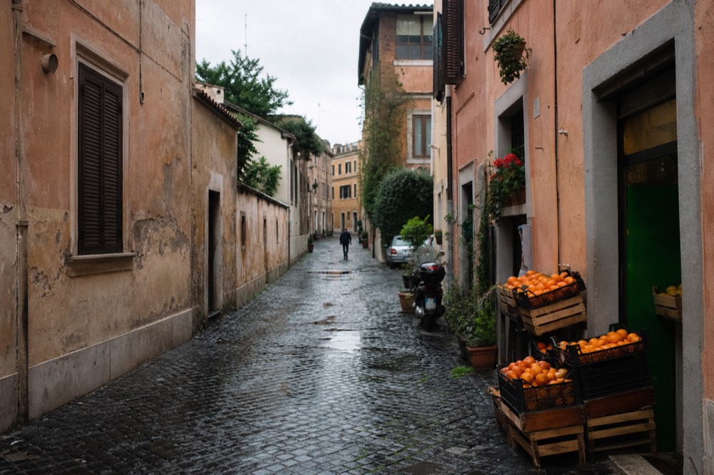Quiet Trastevere side street with shutters, potted plants and a small grocery shop