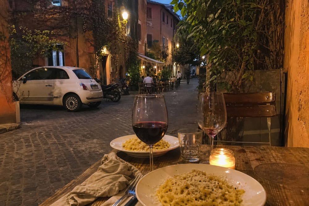 A finished plate of tagliatelle with tomato sauce and basil garnished with pecorino cheese