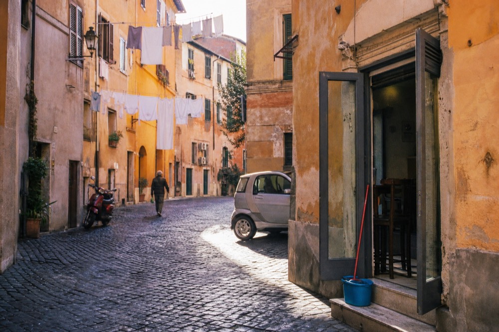 A cobbled Trastevere lane with laundry overhead and a small corner bar