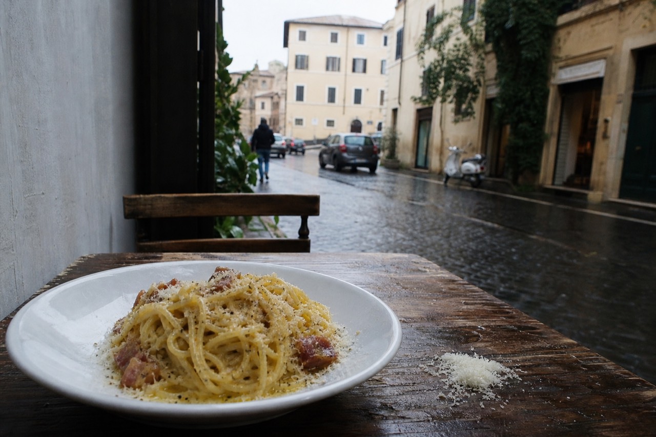 A bowl of spaghetti carbonara with guanciale, pecorino and cracked black pepper on a rustic table