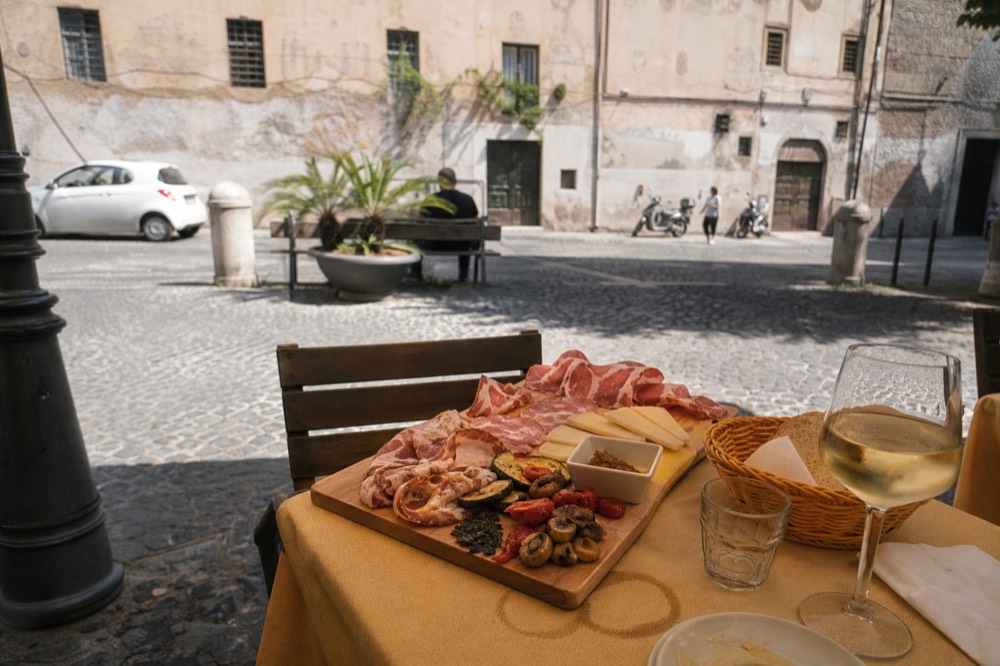 A wooden board of cured meats and cheese on a trattoria table
