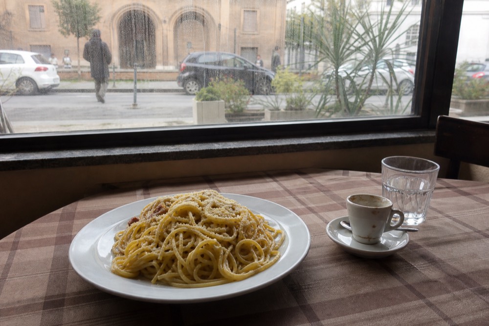 A plate of spaghetti carbonara on a checkered tablecloth