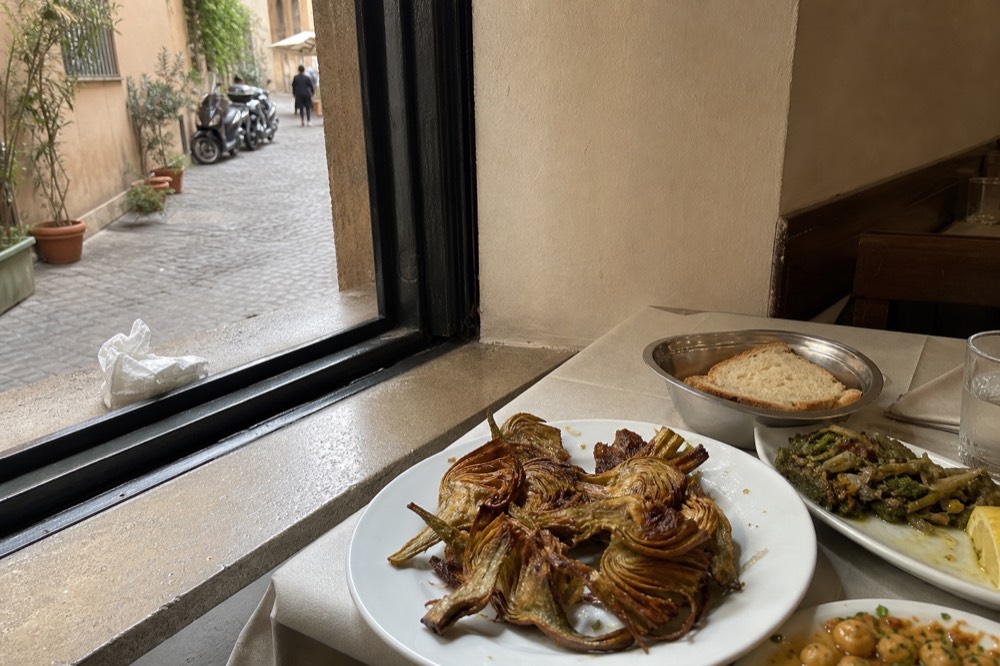 Fried artichokes and other Roman dishes served on a table in a small trattoria dining room