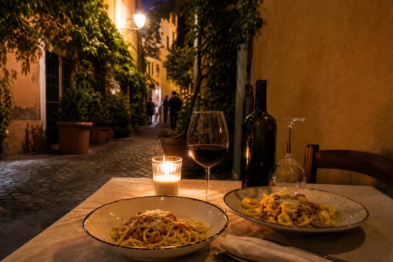 Fresh pasta dishes and a glass of red wine on a trattoria table in a Roman dining room