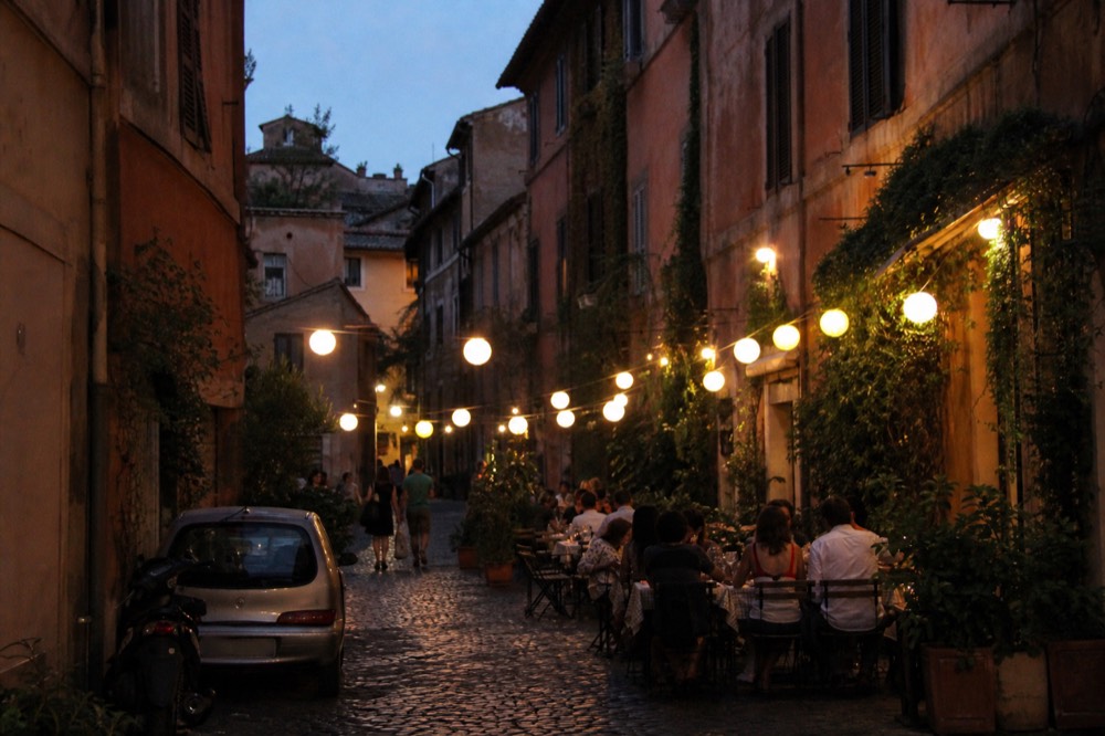 Outdoor dinner tables with paper lanterns on a warm Roman evening street