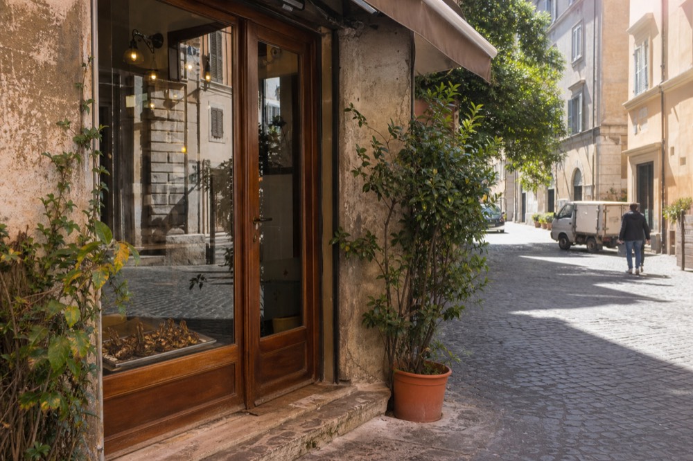 A chalkboard menu on a wall beside a small Roman trattoria door