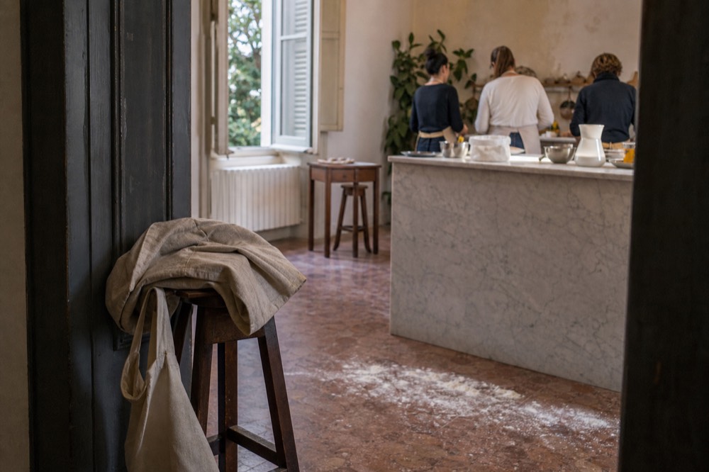A folded jacket and a small bag left on a bench at the edge of a cooking classroom