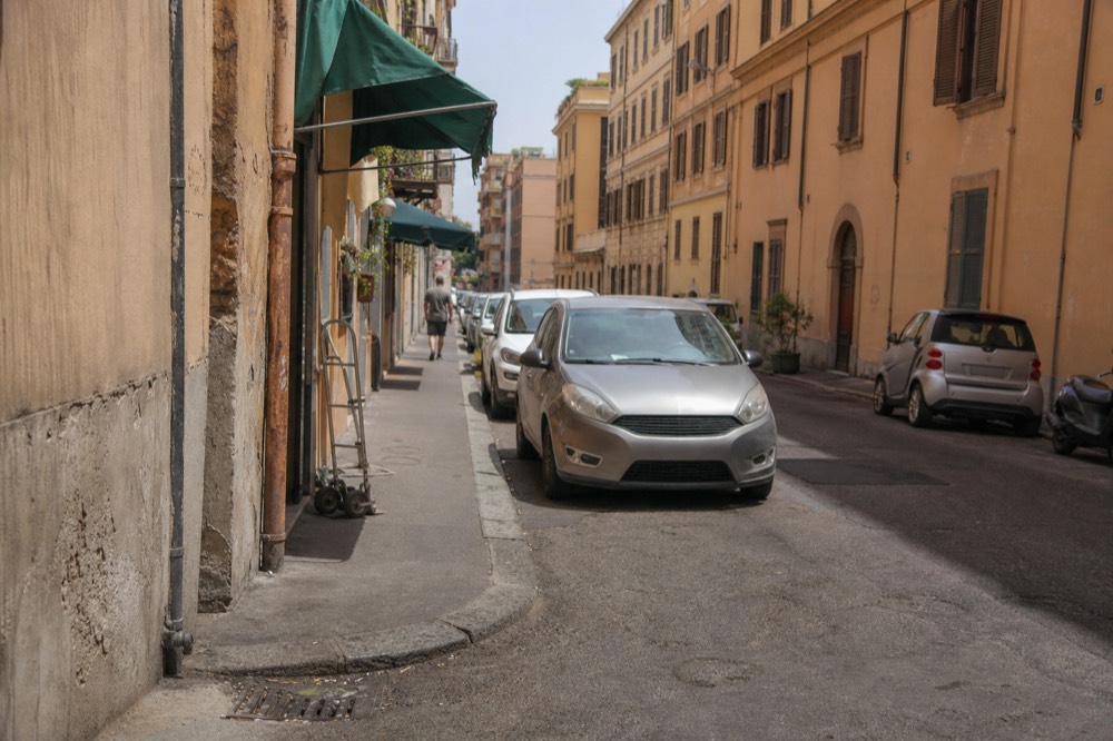A narrow Testaccio street with ochre apartment buildings and trattoria awnings in daylight