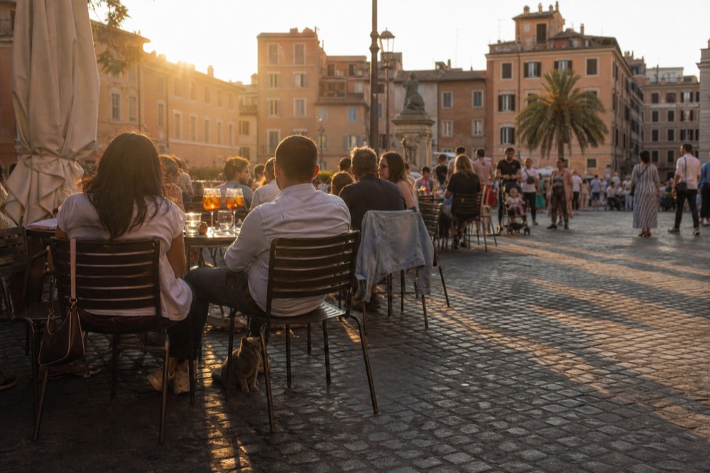 Crowded piazza bar tables at golden hour in Rome