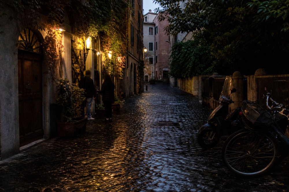Narrow cobbled street with lit wine bar entrances in the evening