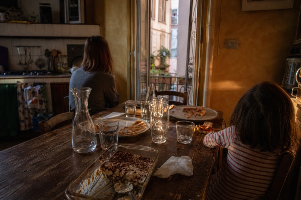 Family sharing a finished pizza and tiramisu at a set table after class