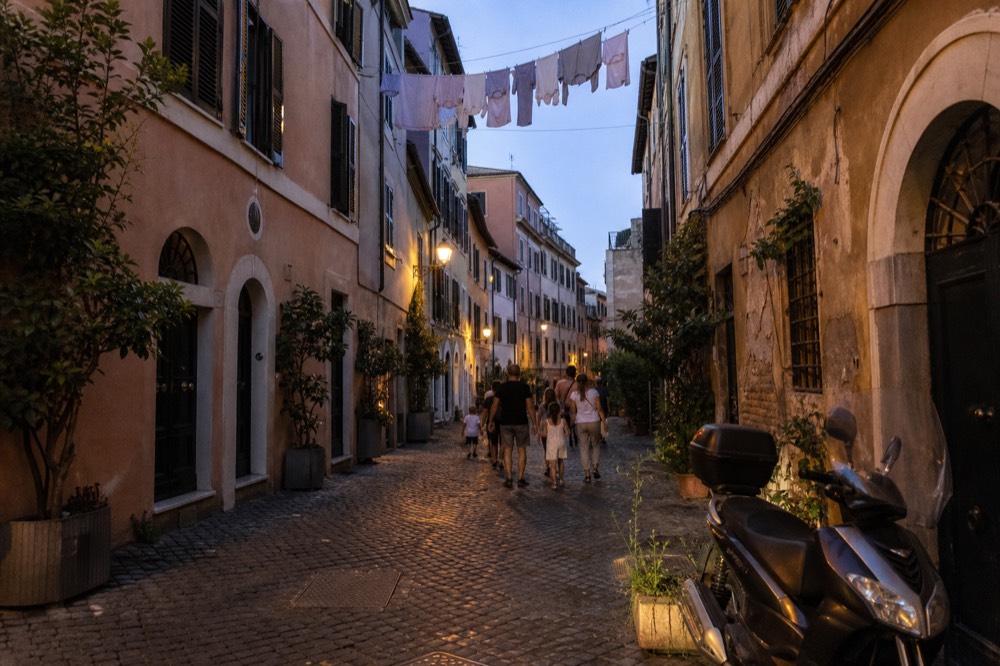 Evening view of a Rome street with families walking to dinner past illuminated facades