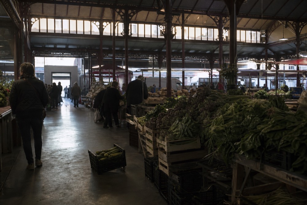 Stalls of fresh vegetables, artichokes and bread inside a covered Rome market hall