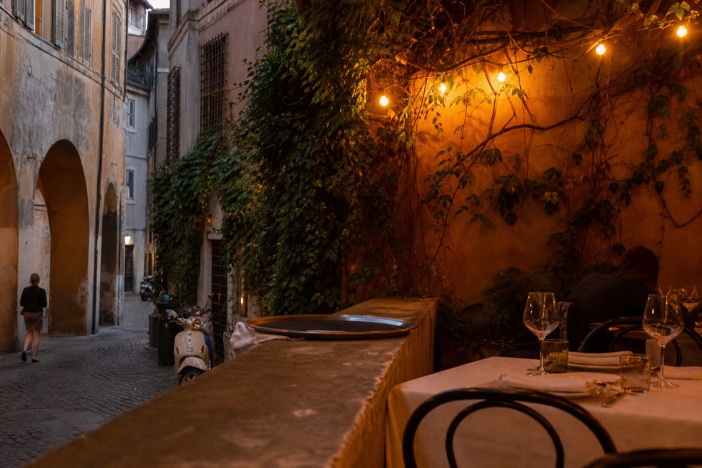 A canal-side restaurant terrace with tables set for dinner