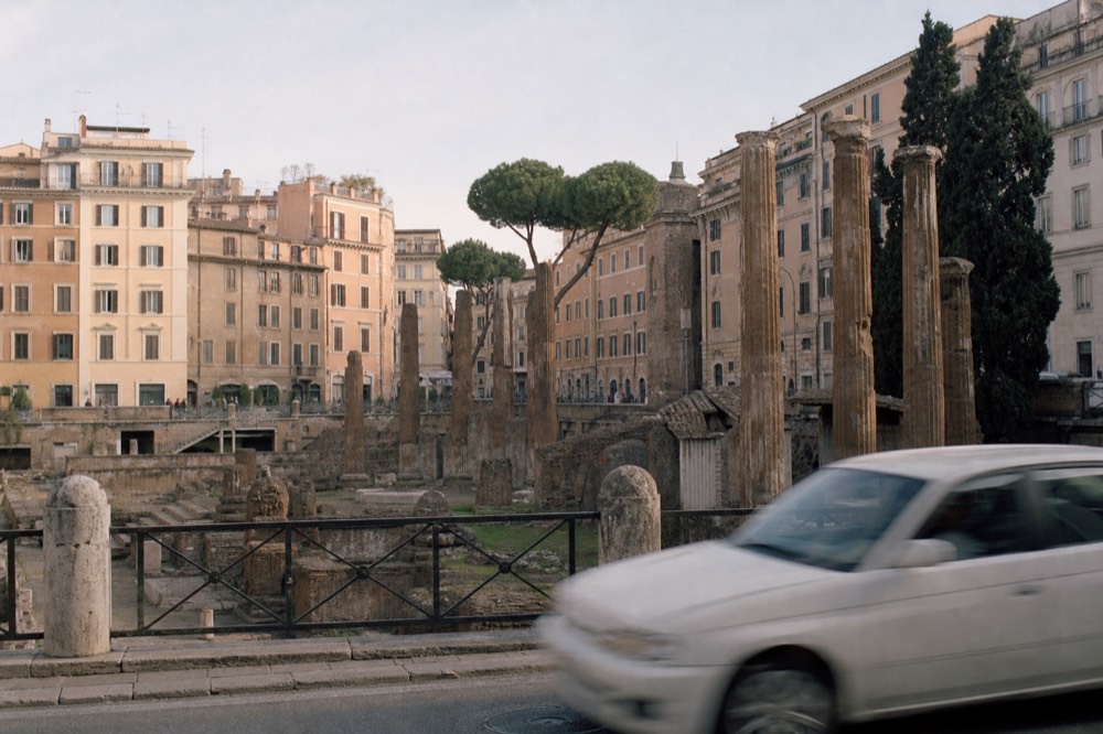 Ancient stone columns standing beside a modern Roman street
