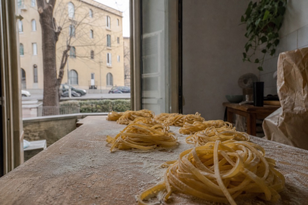 Long ribbons of fresh tagliatelle arranged in nests on a floured wooden board