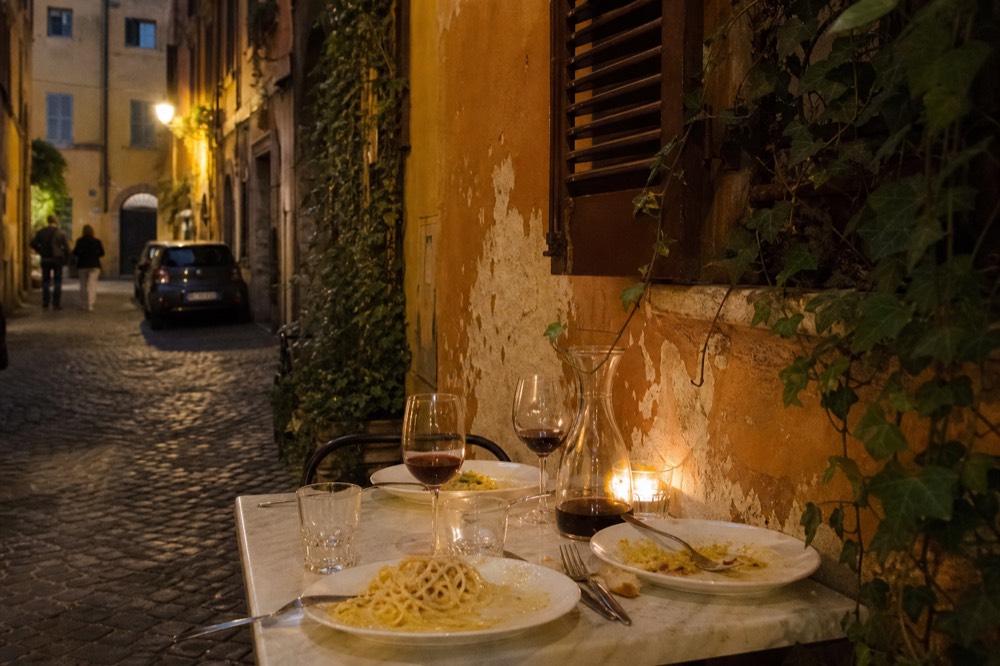 An evening table set with wine glasses and Roman dishes in a Trastevere restaurant