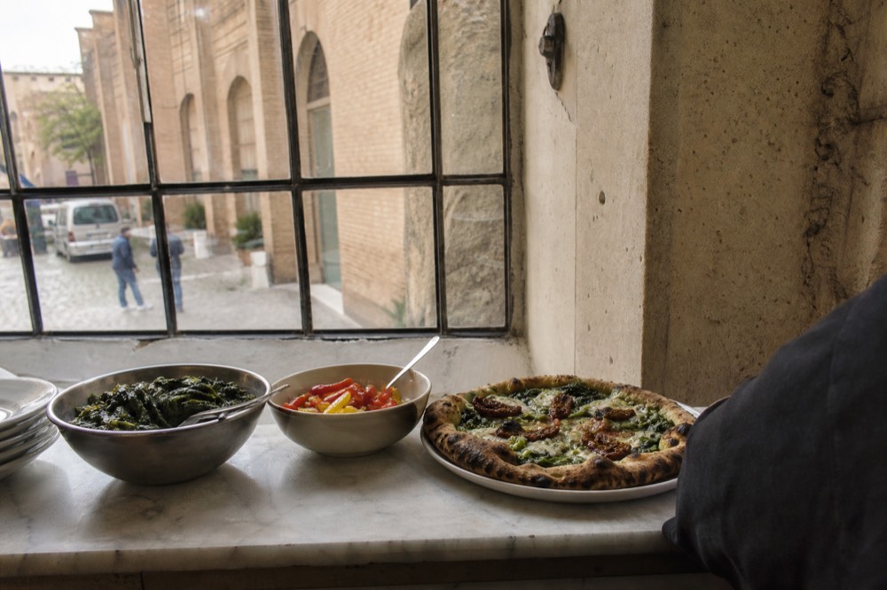 A vegan pizza and vegetable dishes on a Roman restaurant counter