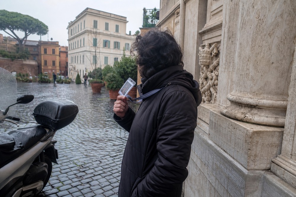 A licensed tour guide showing credentials beside a Roman street sign