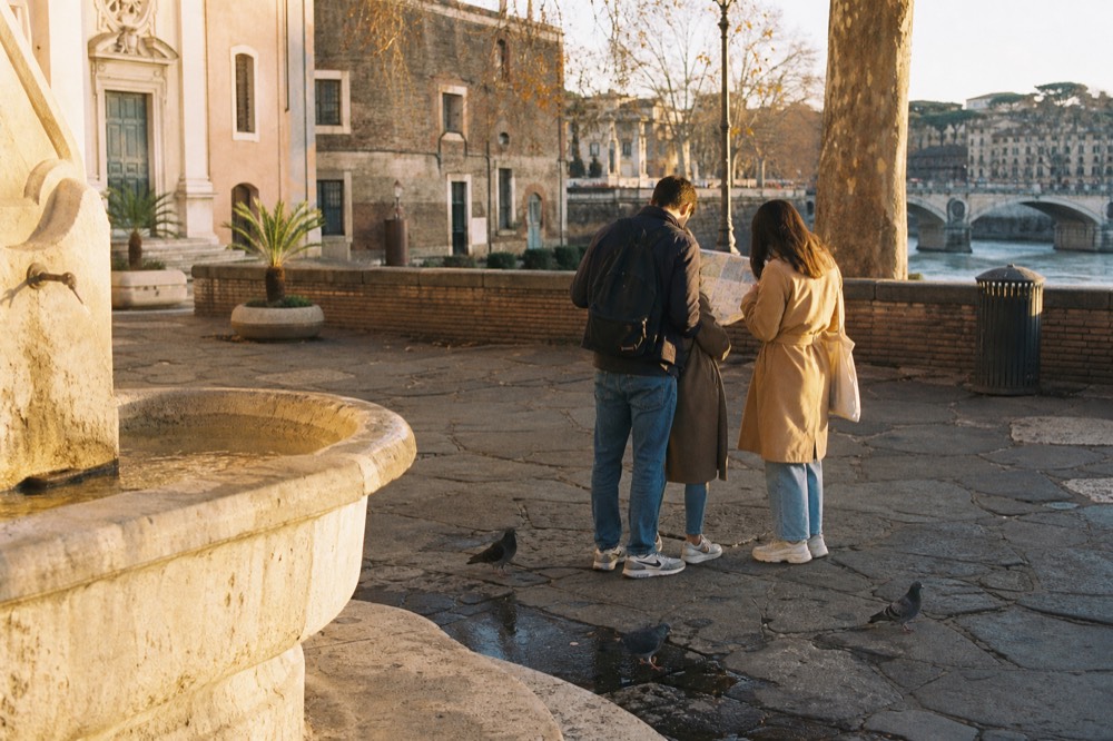 A couple and a guide studying a map at a Roman piazza fountain
