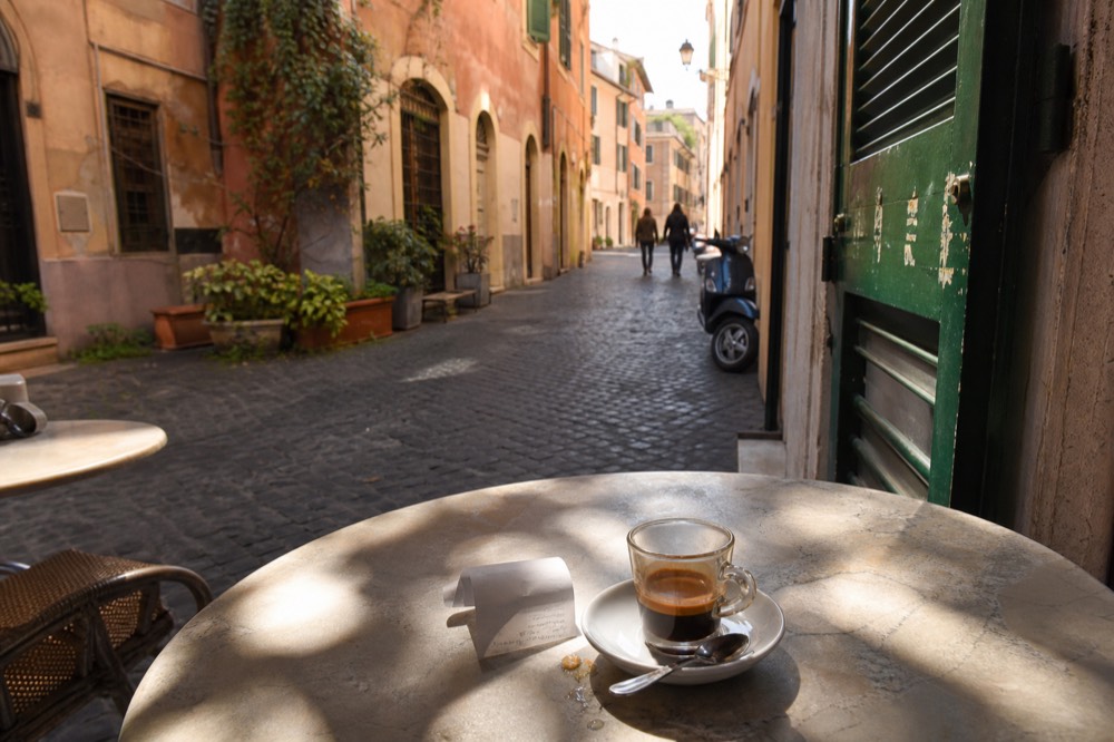 A receipt and espresso cup on a Roman cafe marble table