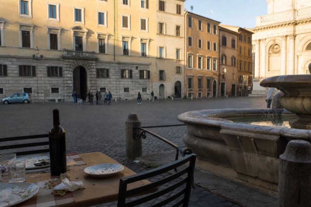 Outdoor table set with wine bottle and plates in a Roman square