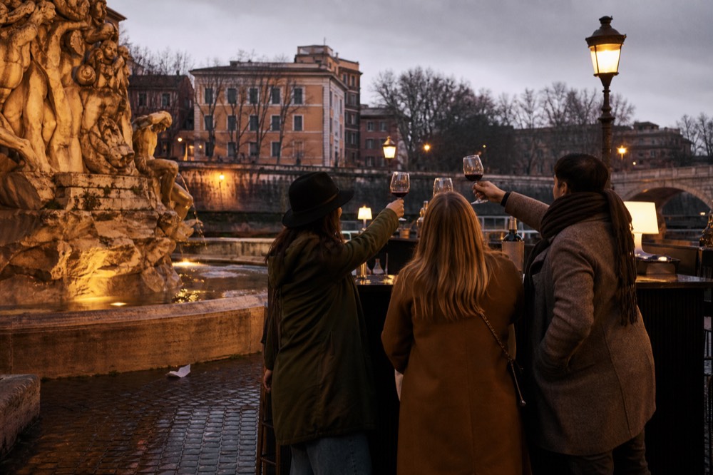 Guide with a small group raising wine glasses at an outdoor counter in Rome