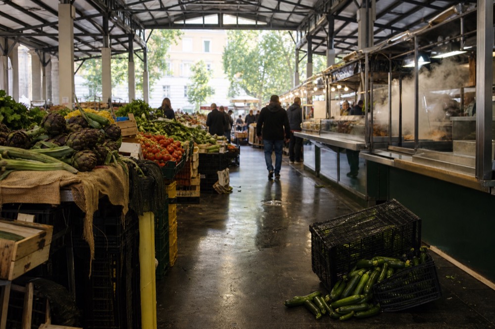 Market stalls with produce and prepared food under the roof of a covered market hall