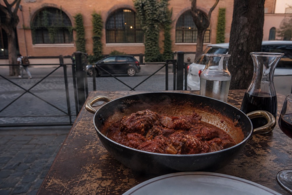 Braised meat dish with tomato sauce served in a rustic pan