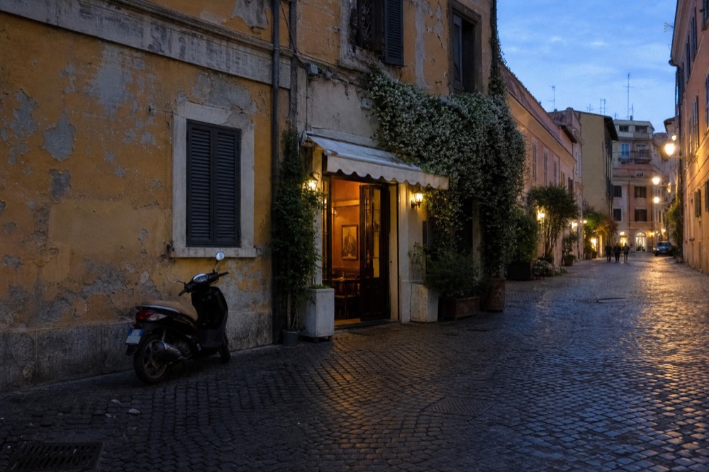 Narrow street with ochre buildings and a traditional trattoria doorway