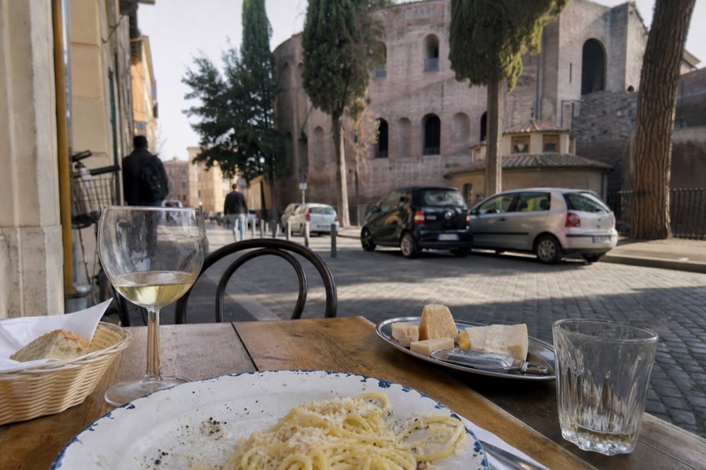 Plate of spaghetti with black pepper and pecorino sauce on a rustic table
