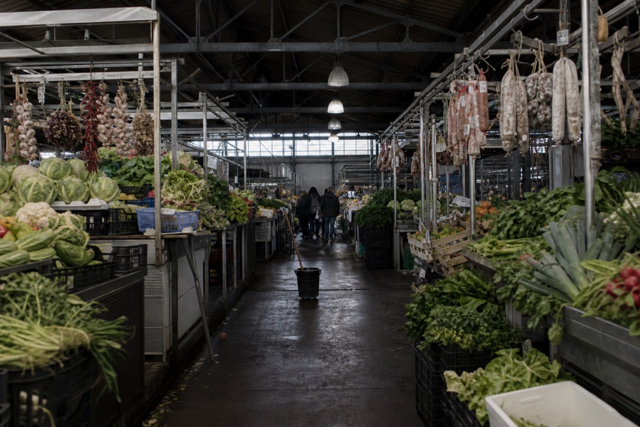 Covered market hall with produce stalls and hanging cured meats
