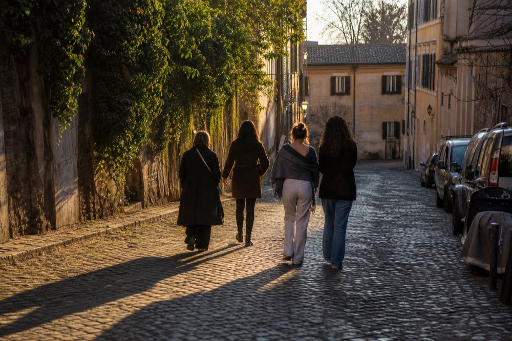 A guide leading a small group down a narrow cobbled lane in central Rome between food stops