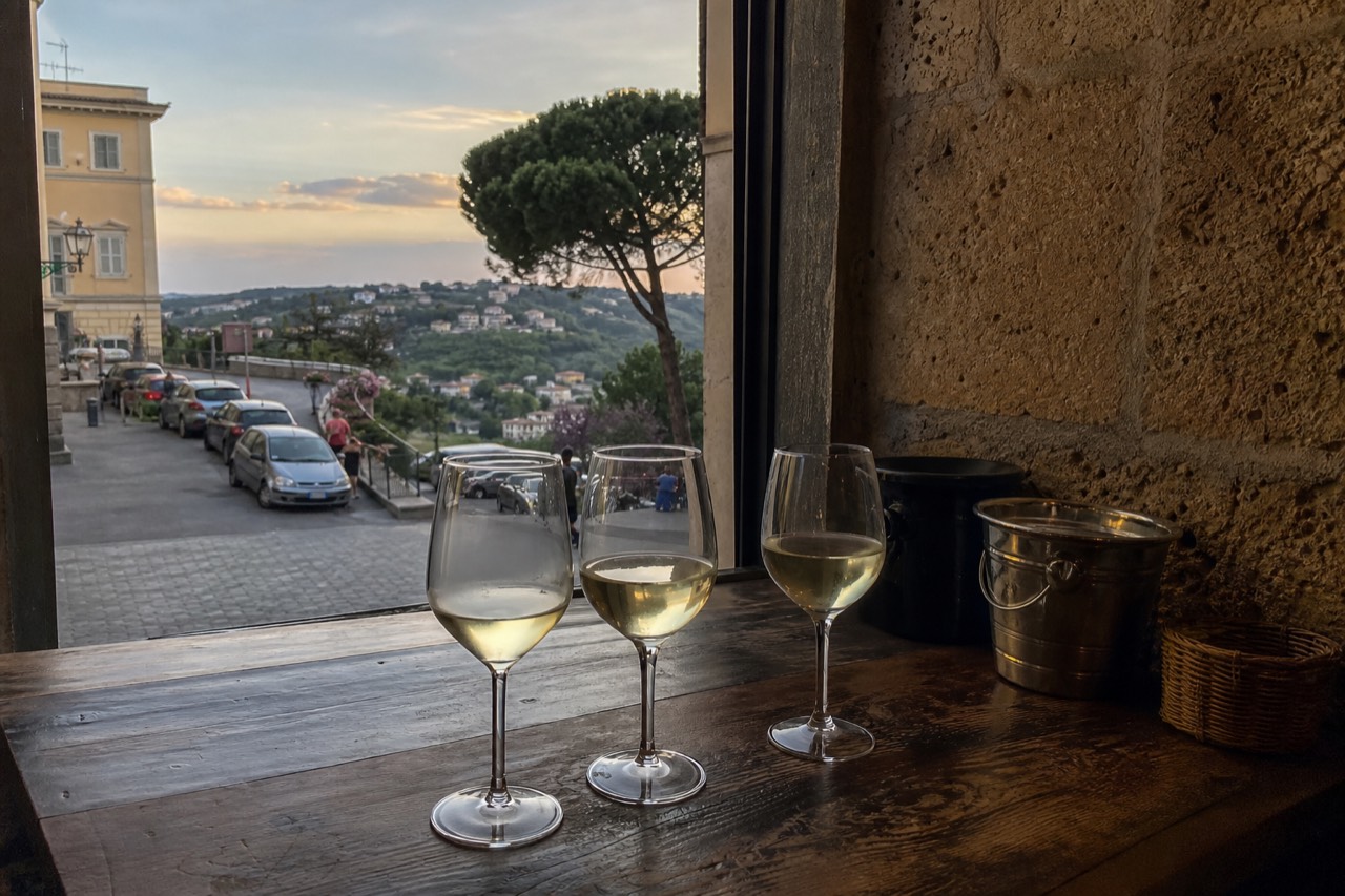 Glasses of white wine on a wooden enoteca counter in Rome
